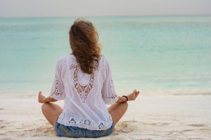 girl meditating on beach